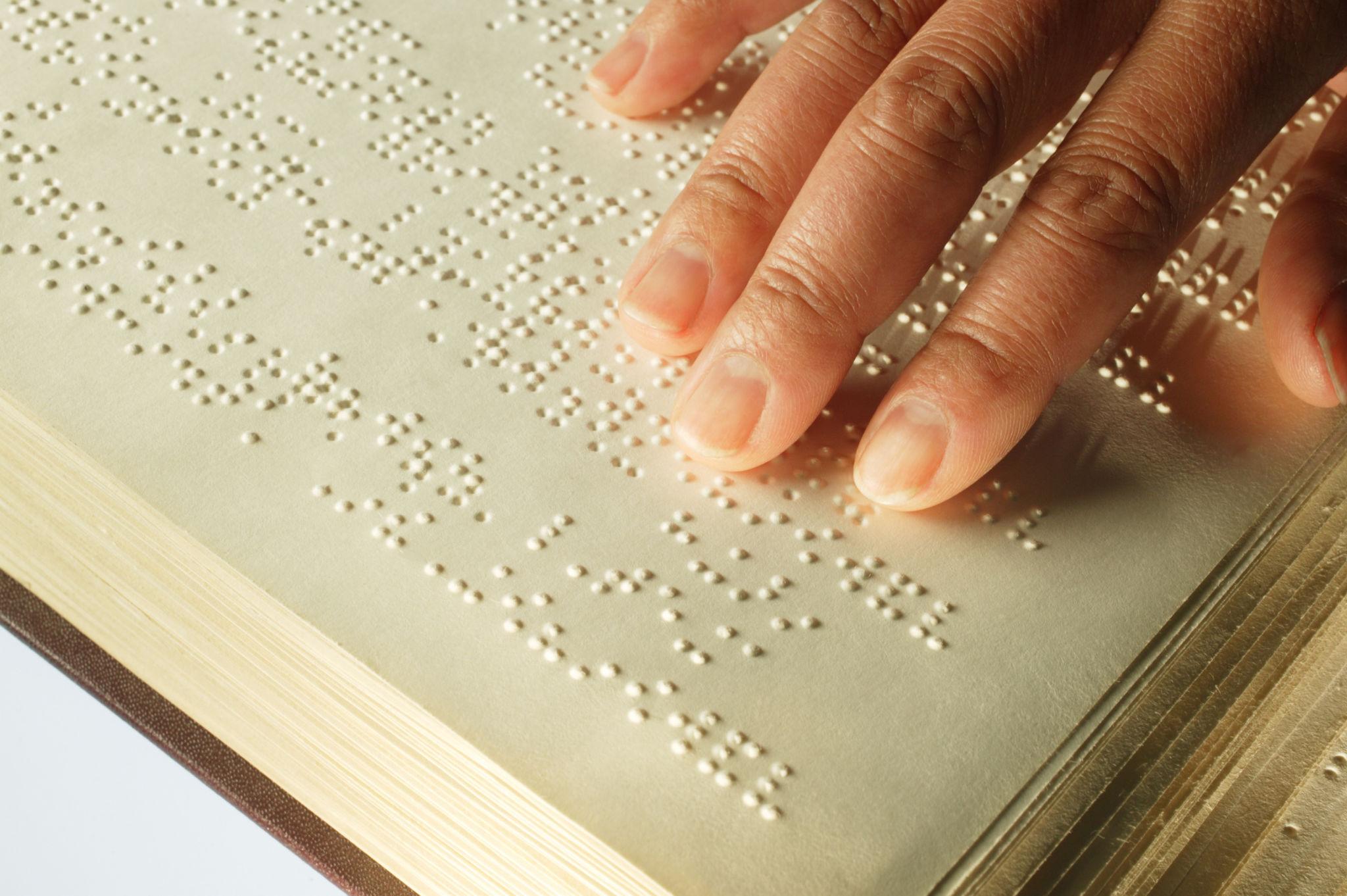 Hands reading an embossed braille document